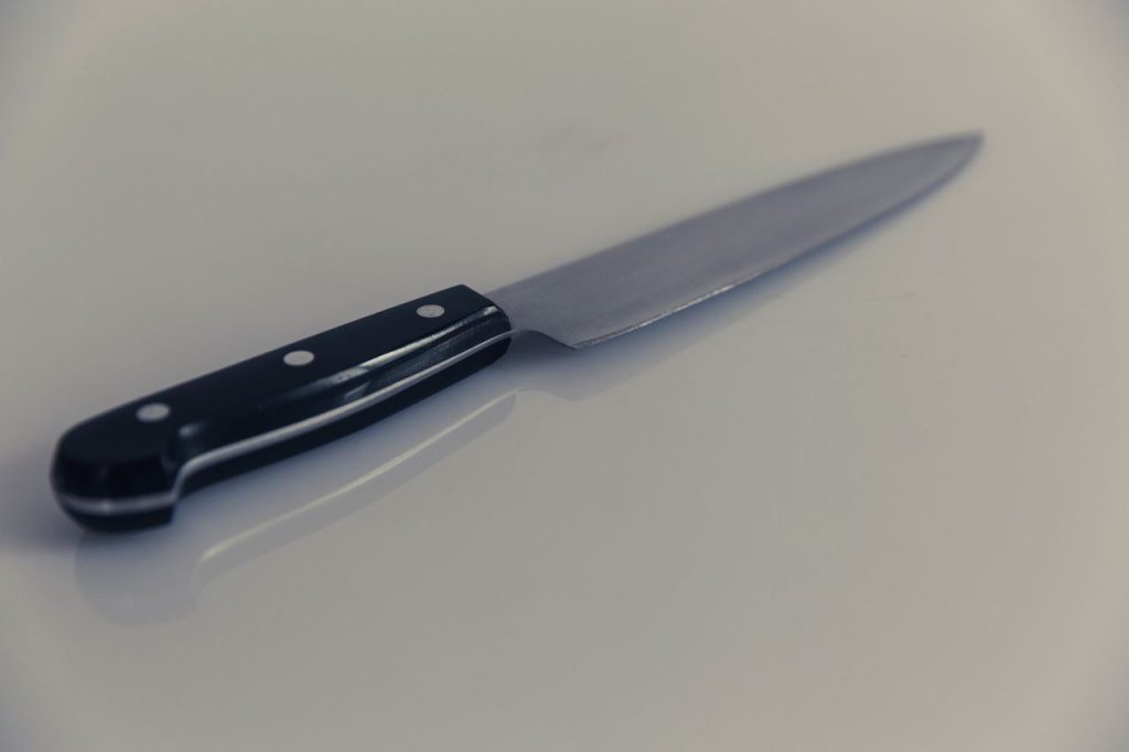 Mastering the First Impression: Your intriguing post title goes here A detailed view of a stainless steel kitchen knife reflecting light on a white surface.